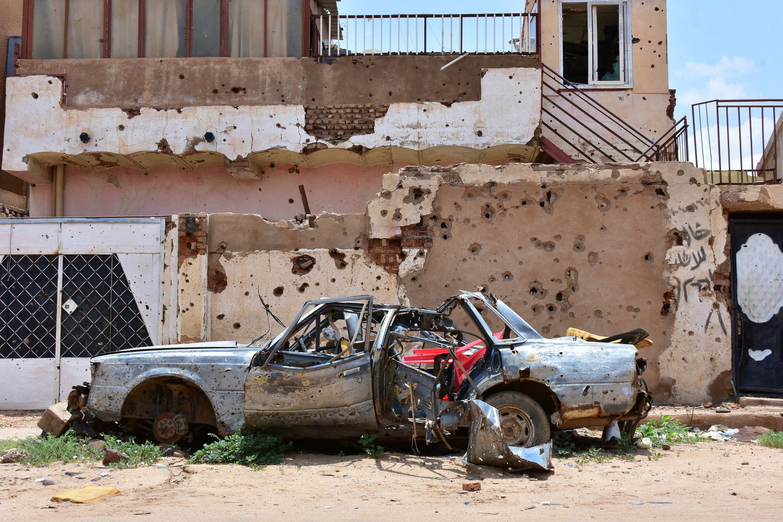 Ein zerstörtes Auto steht im sudanesischen Omdurman vor einem Haus voller Einschüsse. (Archivbild)