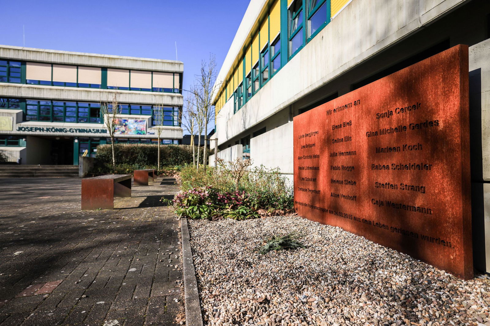 Am Joseph-König-Gymnasium steht eine Gedenktafel direkt am Schulhof, davor wird in den Pausen getobt und gelacht - ein Symbol dafür, dass die Toten weiterhin Teil der Schule sind.