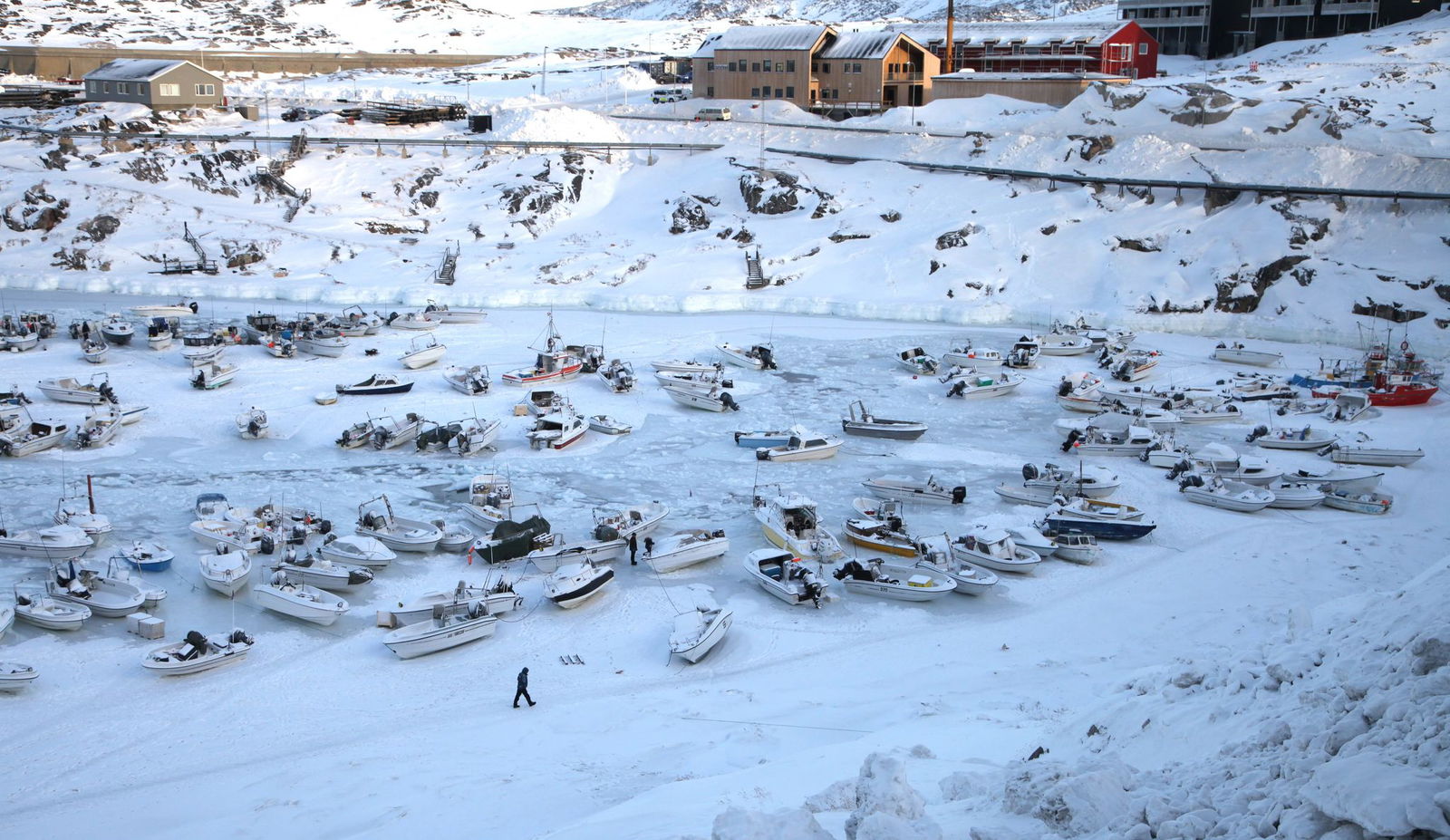 Ein Mann geht im Hafen über das zugefrorene Wasser.