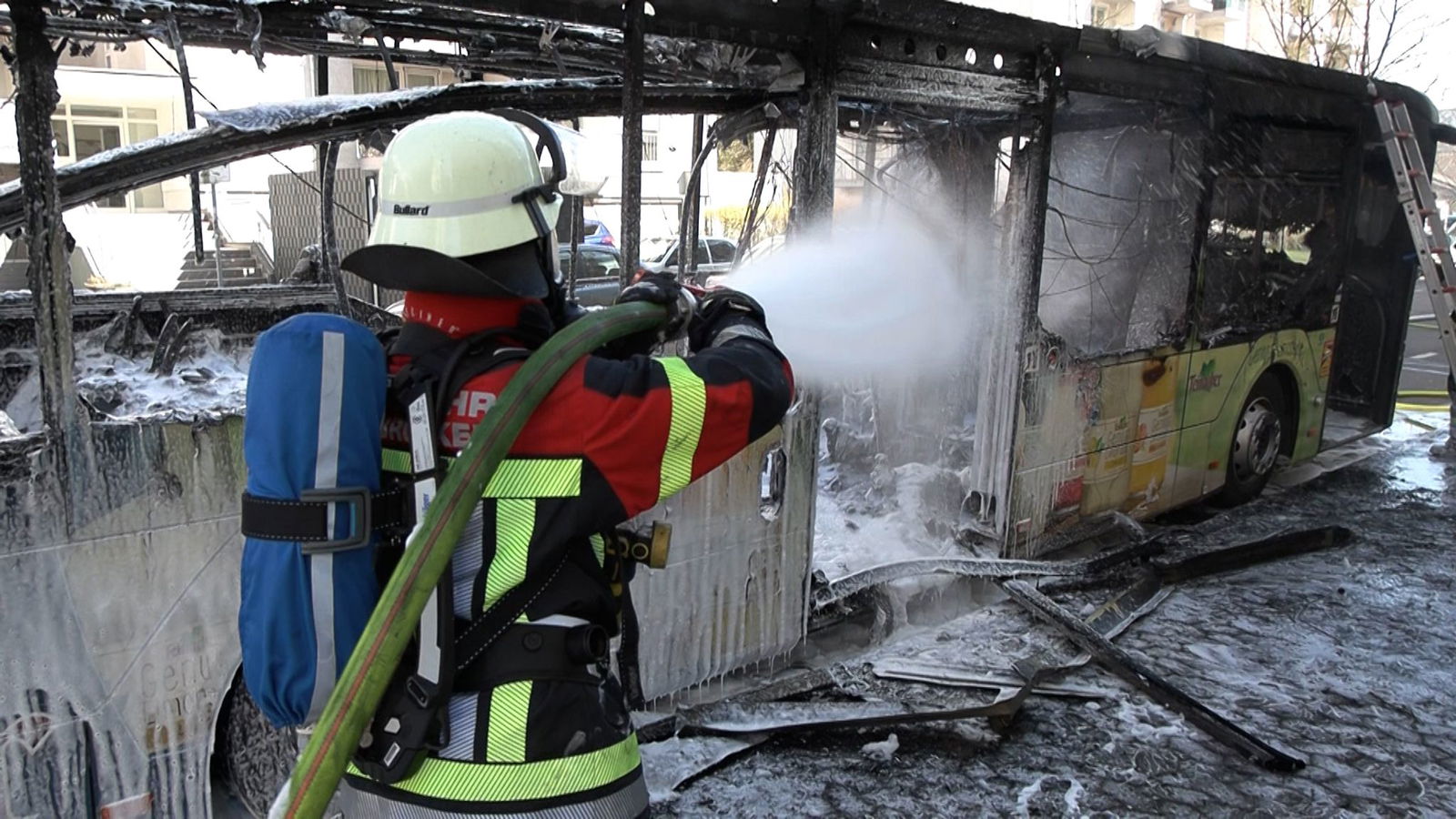 Ein Feuerwehrmann löscht einen in Brand geratenen Bus. 