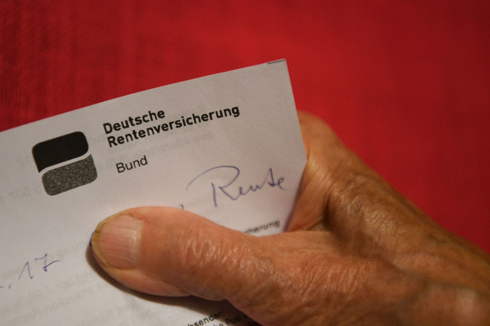 Eine Rentnerin hält ihren Rentenbescheid in der Hand.