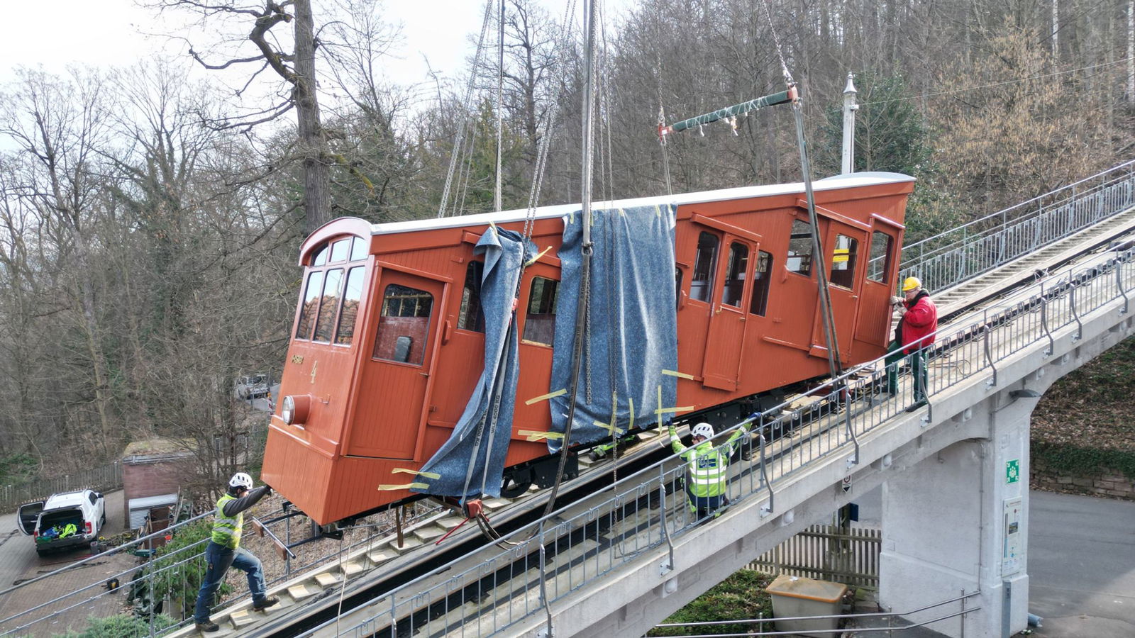 Ein Kran hebt einen Wagen der Heidelberger Bergbahnen nach einer großen Revision in der Schweiz wieder ins Gleis. Ende März soll der Betrieb wieder starten, nach fast drei Monaten Pause.