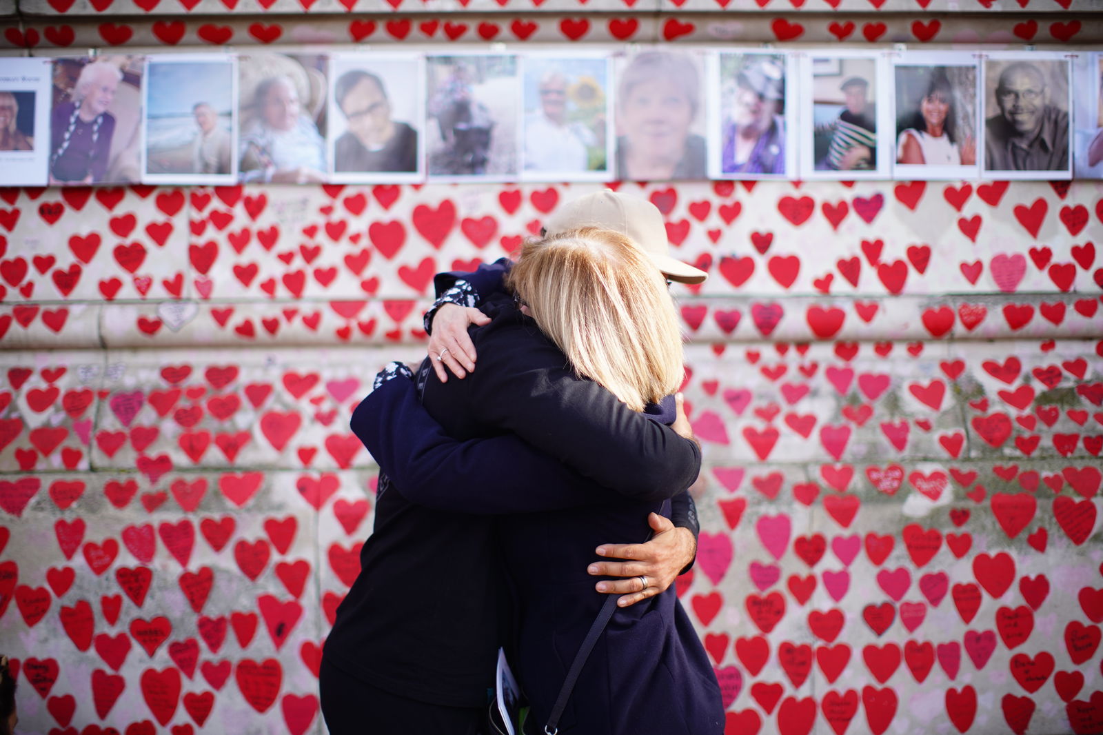 Menschen umarmen sich, während sie an einer Zeremonie zum fünften Jahrestag der Covid-19-Pandemie an der National Covid Memorial Wall in London teilnehmen.