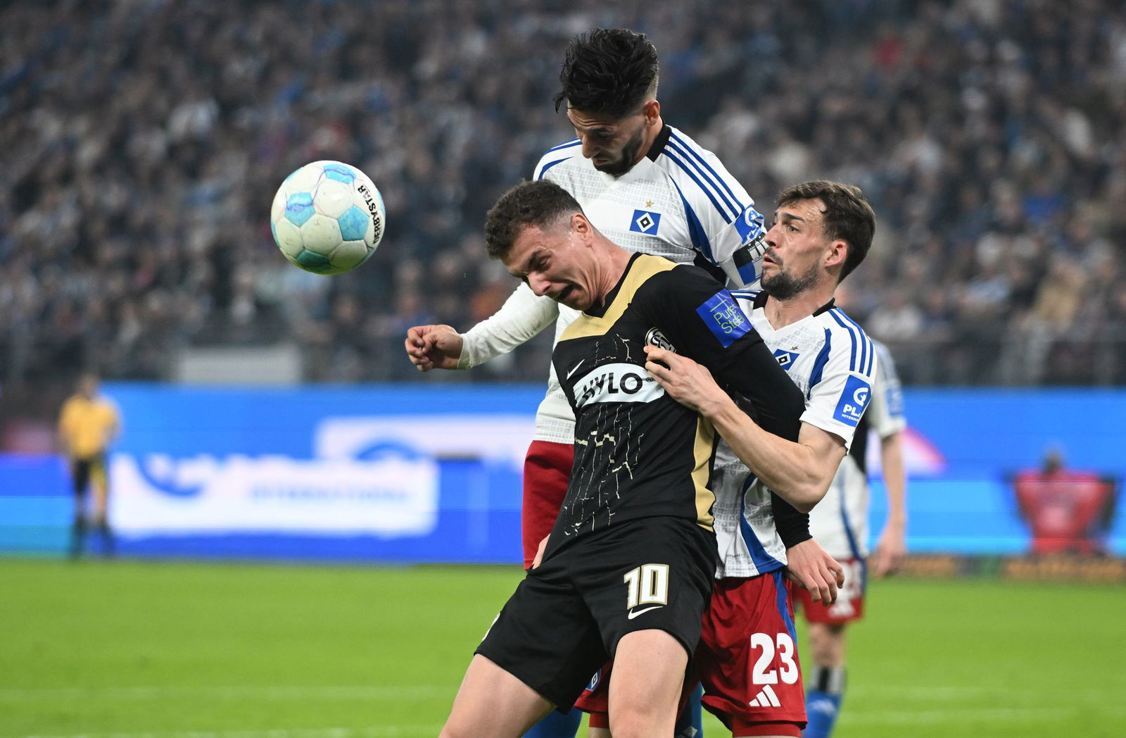 Elversbergs Fisnik Asllani (vorn, l) wird von den beiden HSV-Spieler Ludovit Reis und Jonas Meffert geblockt.