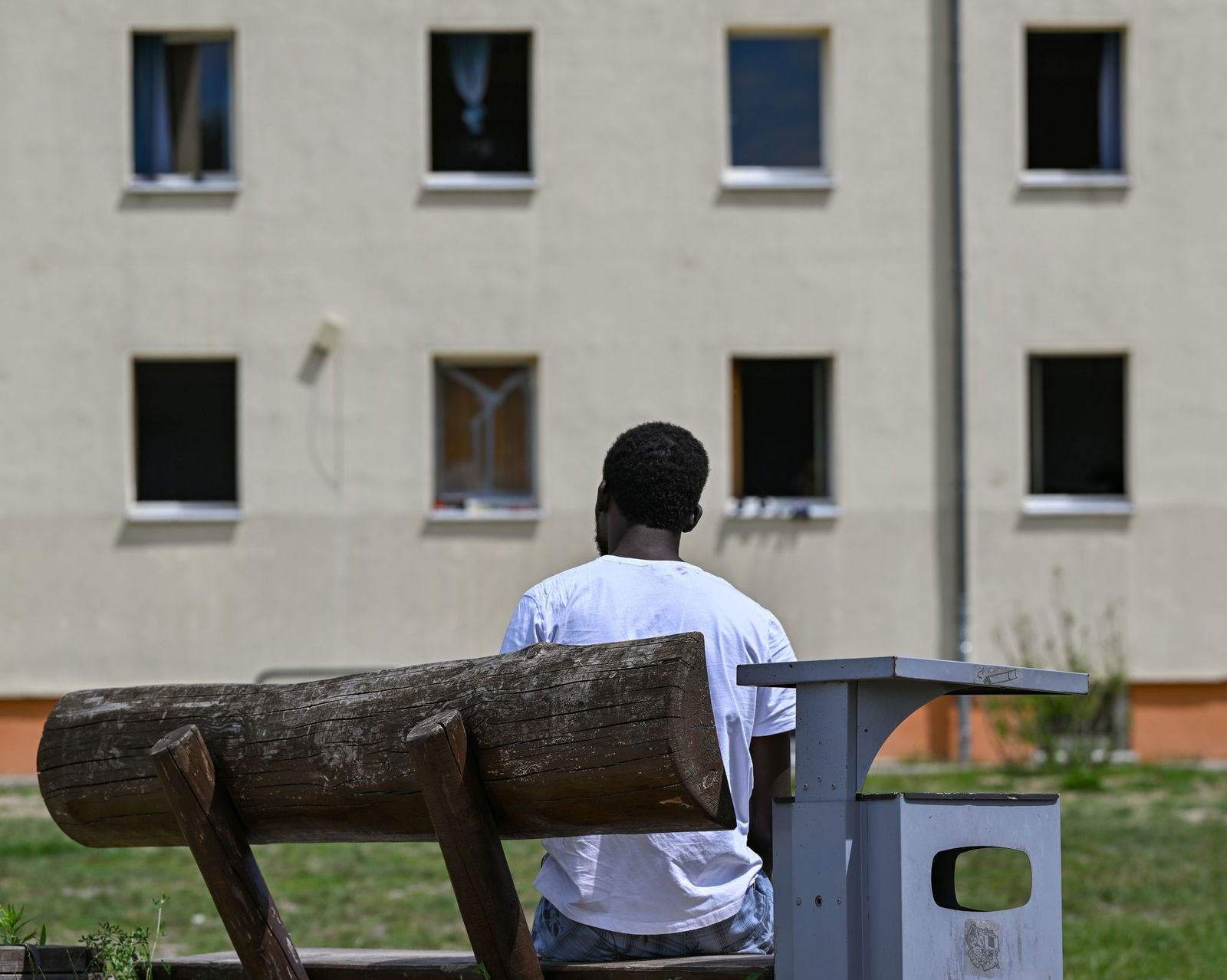 Ein Migrant sitzt auf einer Bank auf dem Gelände der Zentralen Erstaufnahmeeinrichtung für Asylbewerber des Landes Brandenburg in Eisenhüttenstadt. (Archivfoto)