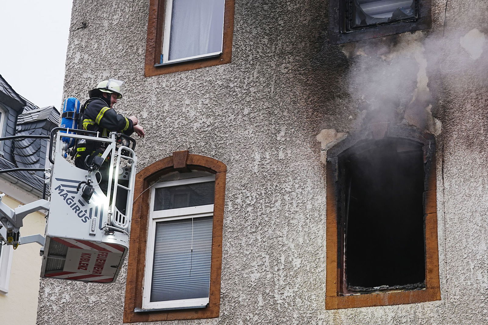 Rauch steigt aus dem Fenster des Mehrfamilienhauses auf.