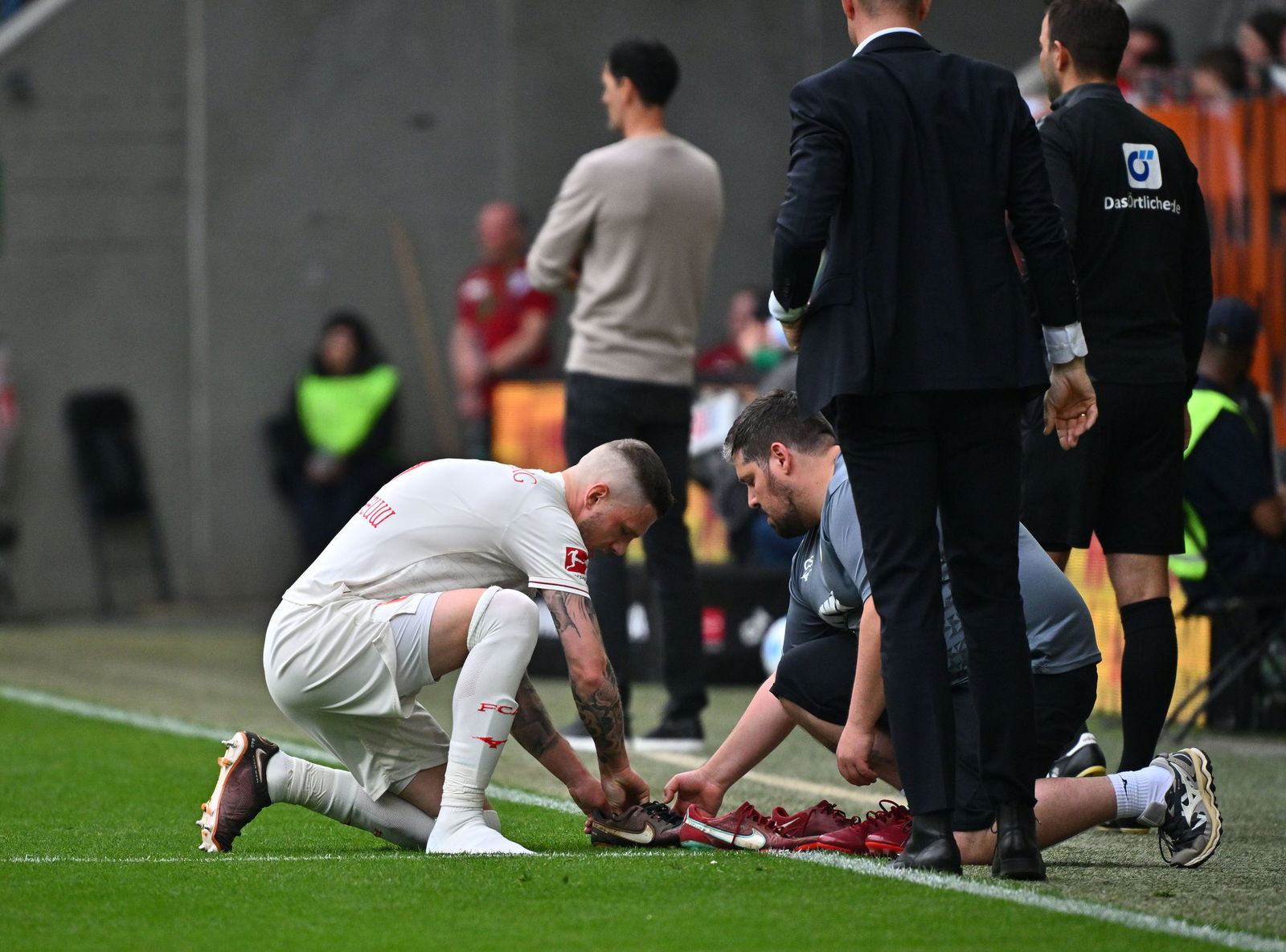 Schuhwechsel mitten im Spiel: FCA-Kapitän Jeffrey Gouweleeuw.