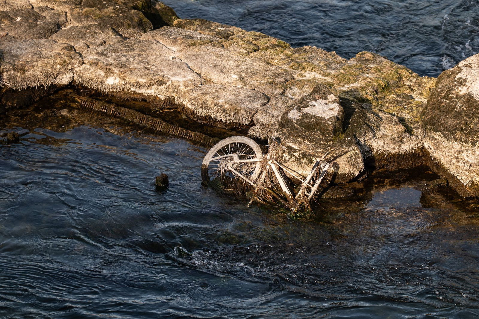 Ein Fahrrad liegt bei Niedrigwasser im Wasser am Rheinfall in Schaffhausen.