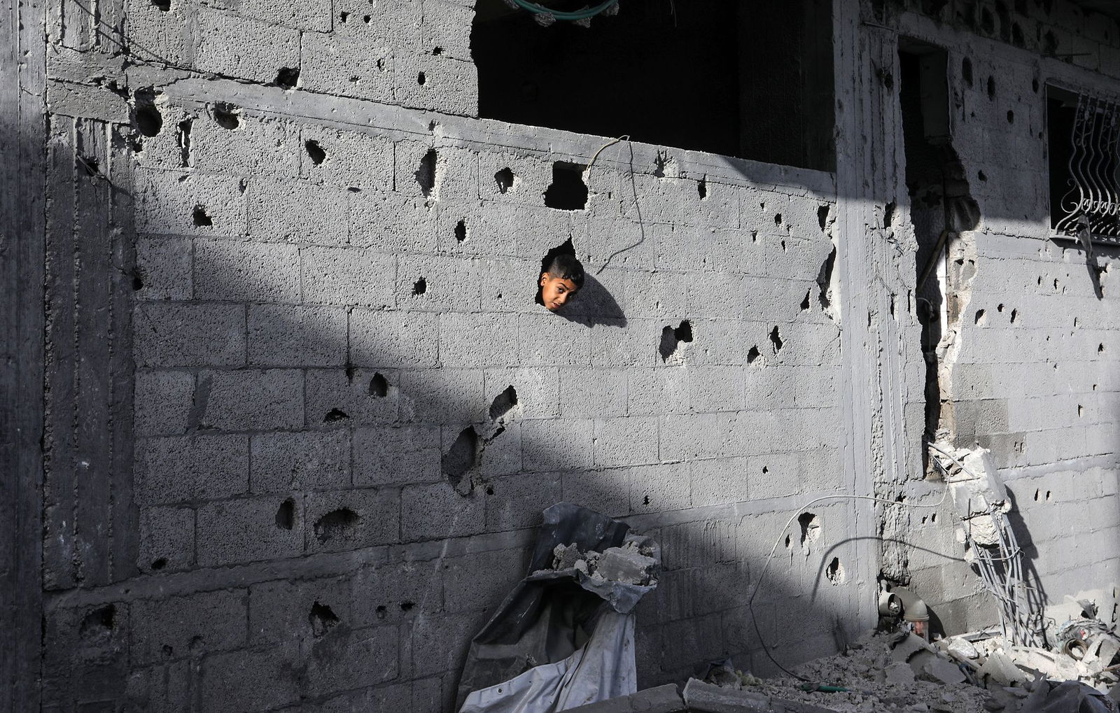 Ein palästinensisches Kind schaut aus einem Loch in einem Gebäude in Chan Junis, das durch einen israelischen Luftangriff beschädigt wurde