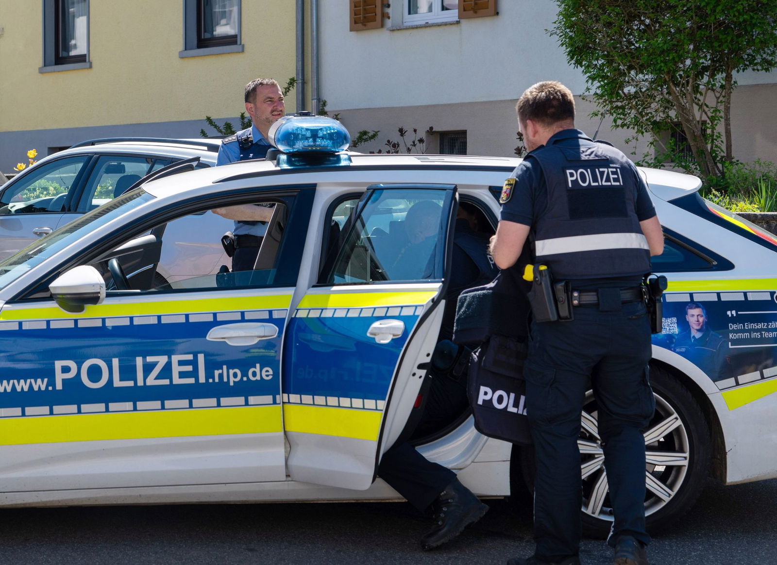 Polizisten sind vor einem Haus im Einsatz.