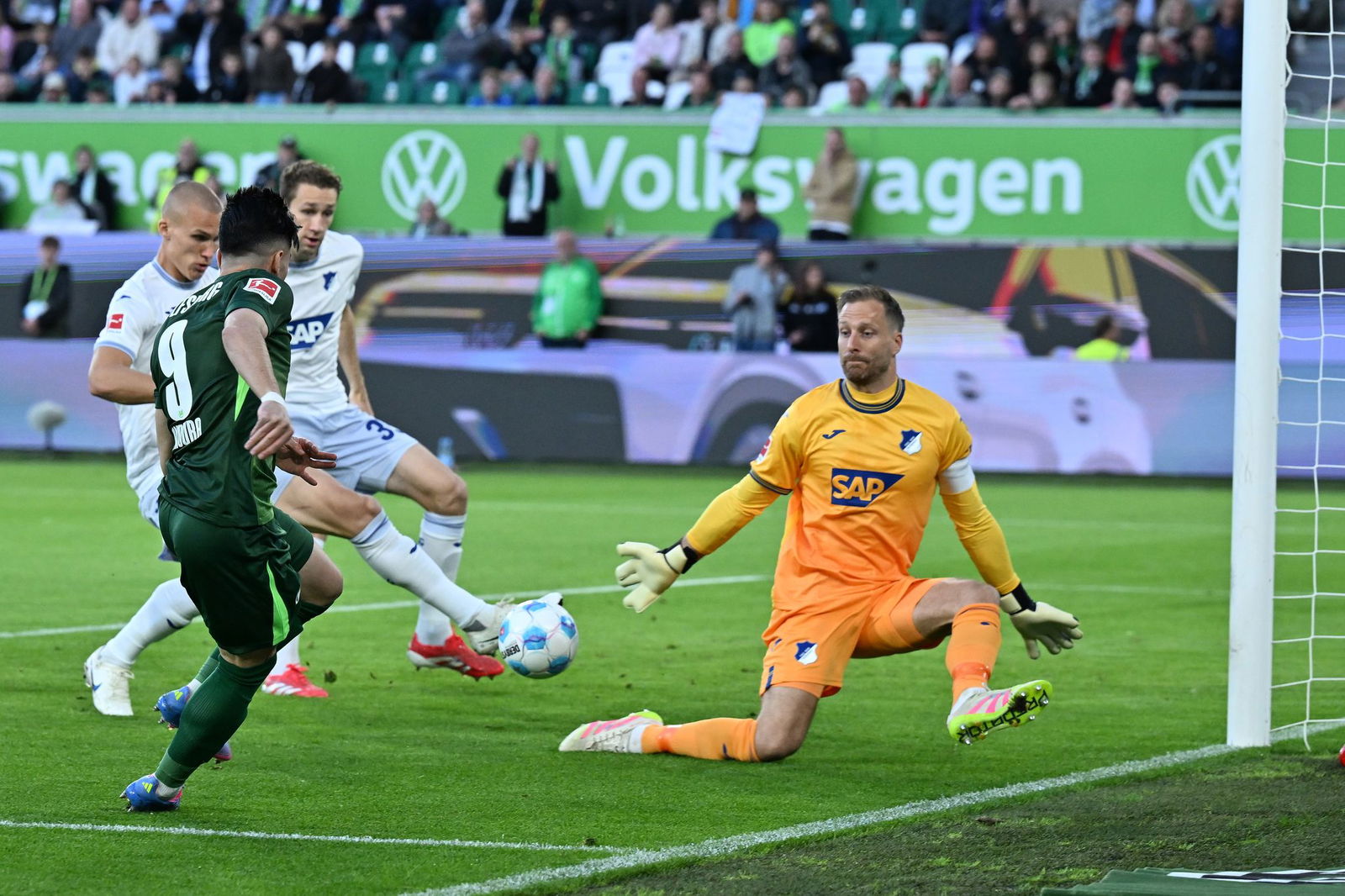 Das Wolfsburger Führungstor: Mohamed Amoura bringt den Ball in die Mitte, Leo Östigaard (l) trifft ins eigene Tor.