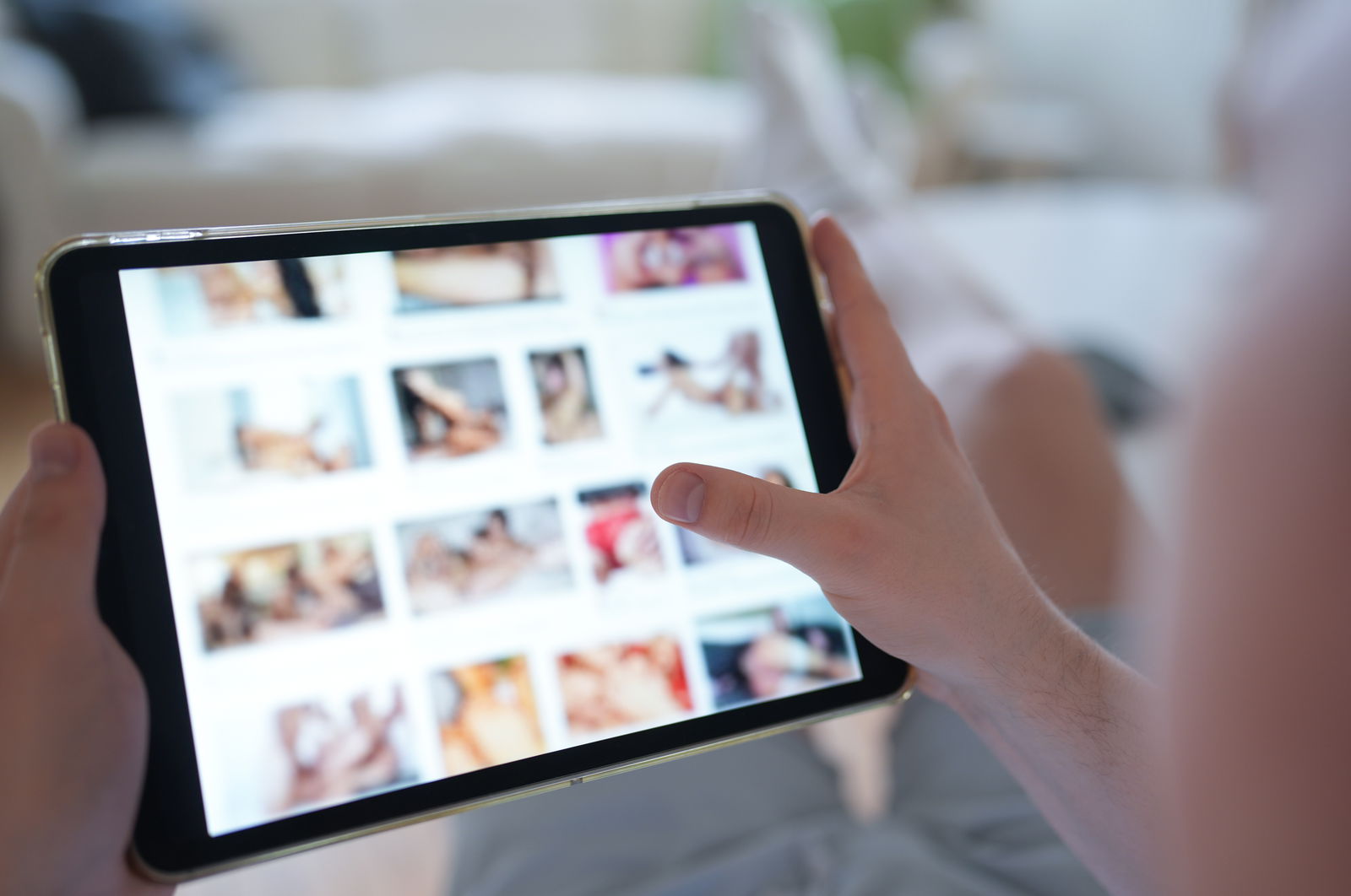 Ein junger Mann schaut sich auf einem Smartphone eine Porno-Internetseite an (gestellte Szene). Immer mehr Frauen und Mädchen werden Opfer von Deepfake-Pornos.