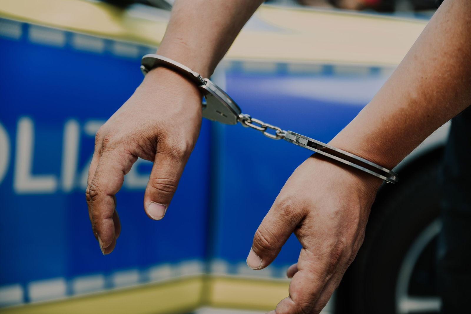 Streifenwagen mit Händen in Handschellen