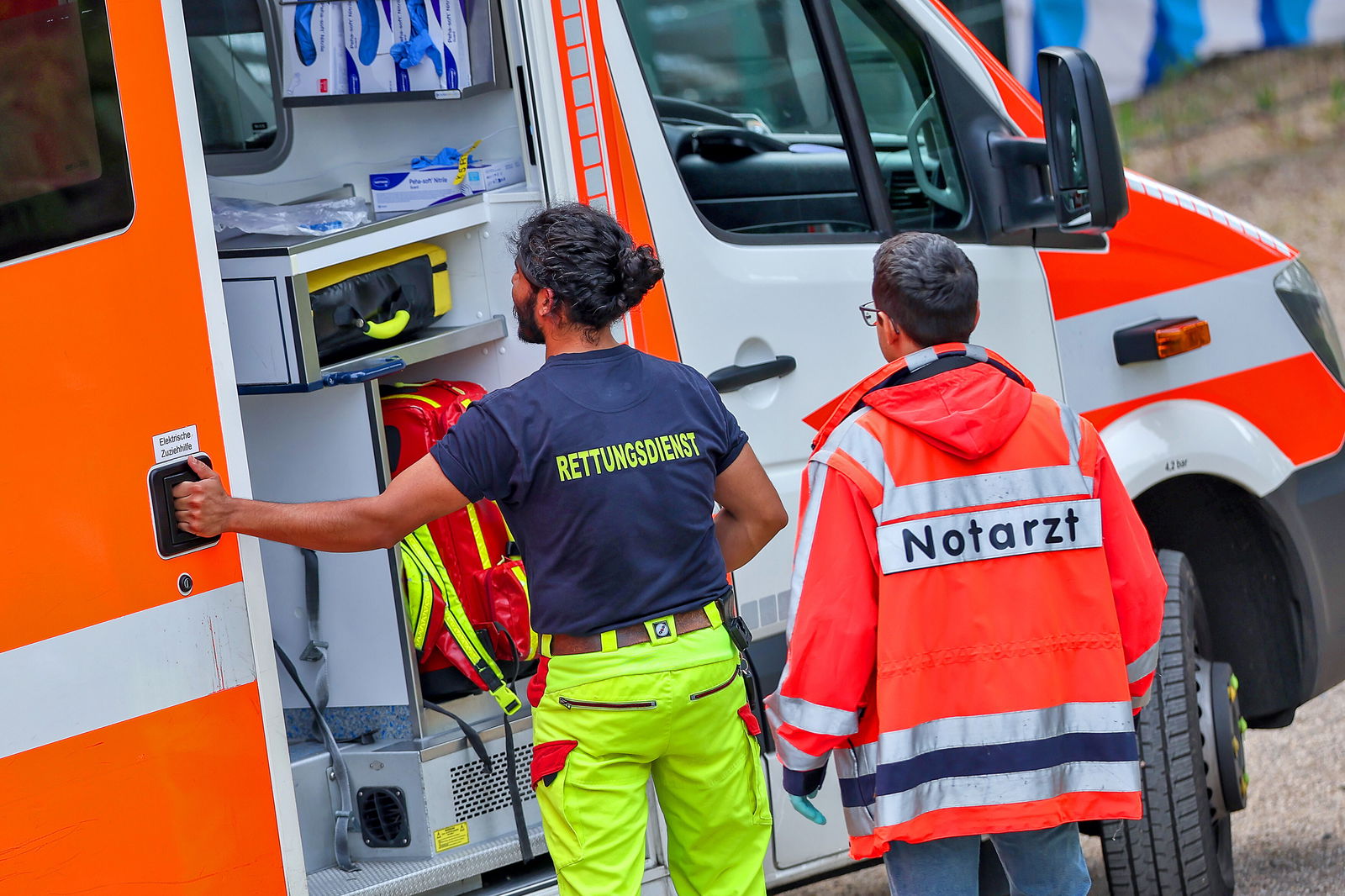 Ein Rettungssanitäter und ein Notarzt stehen vor einem Rettungswagen