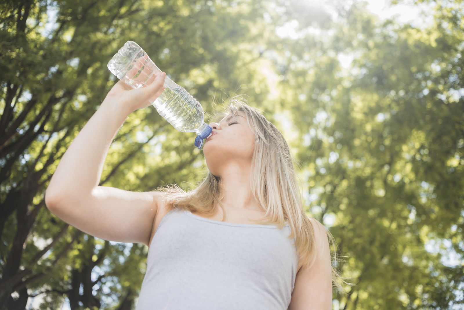 Frau trinkt aus einer Flasche Wasser