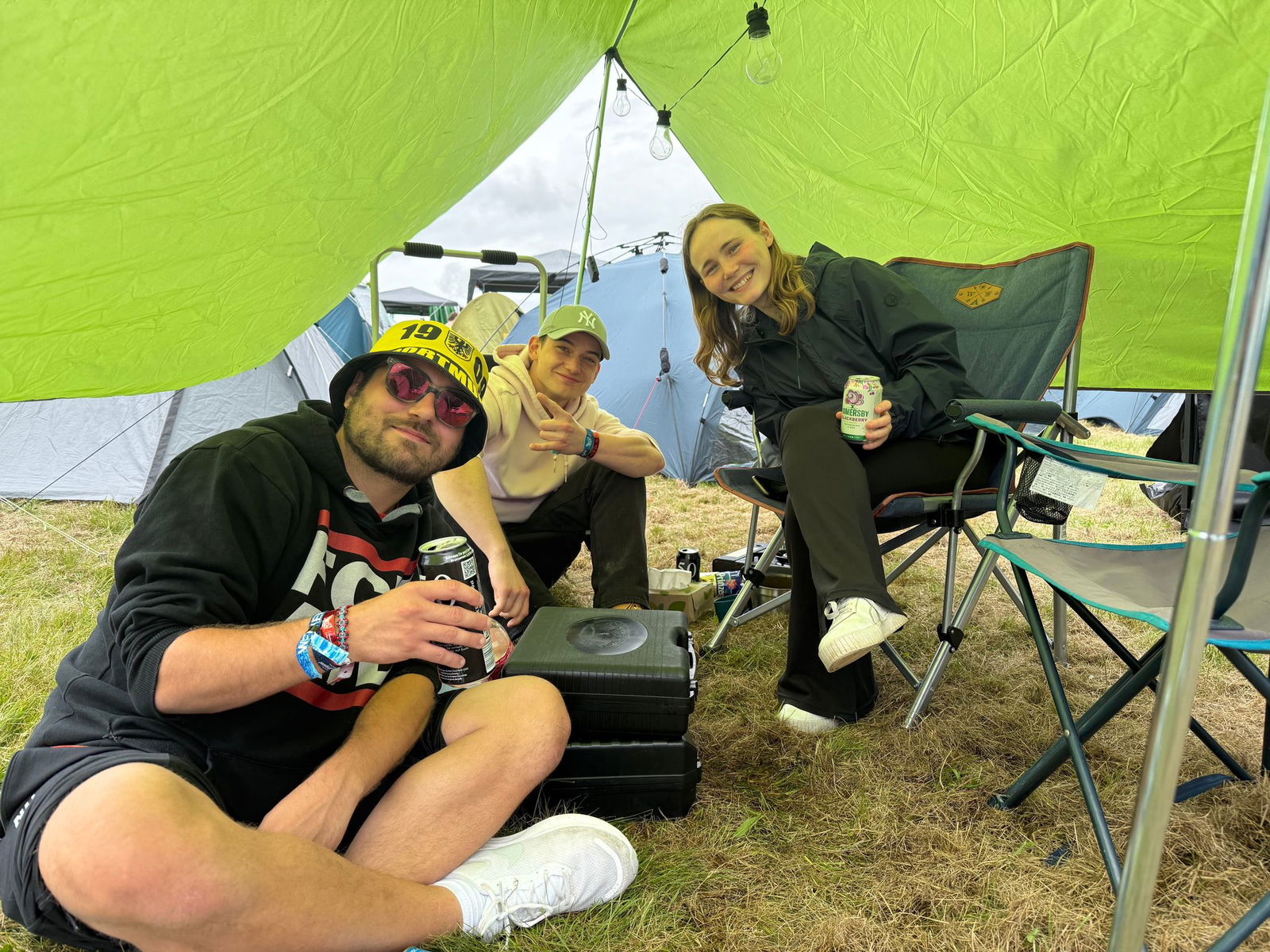 Noch sporadisch sitzen die Freunde Nico, Felix und July (l-r) unter einer Plane.