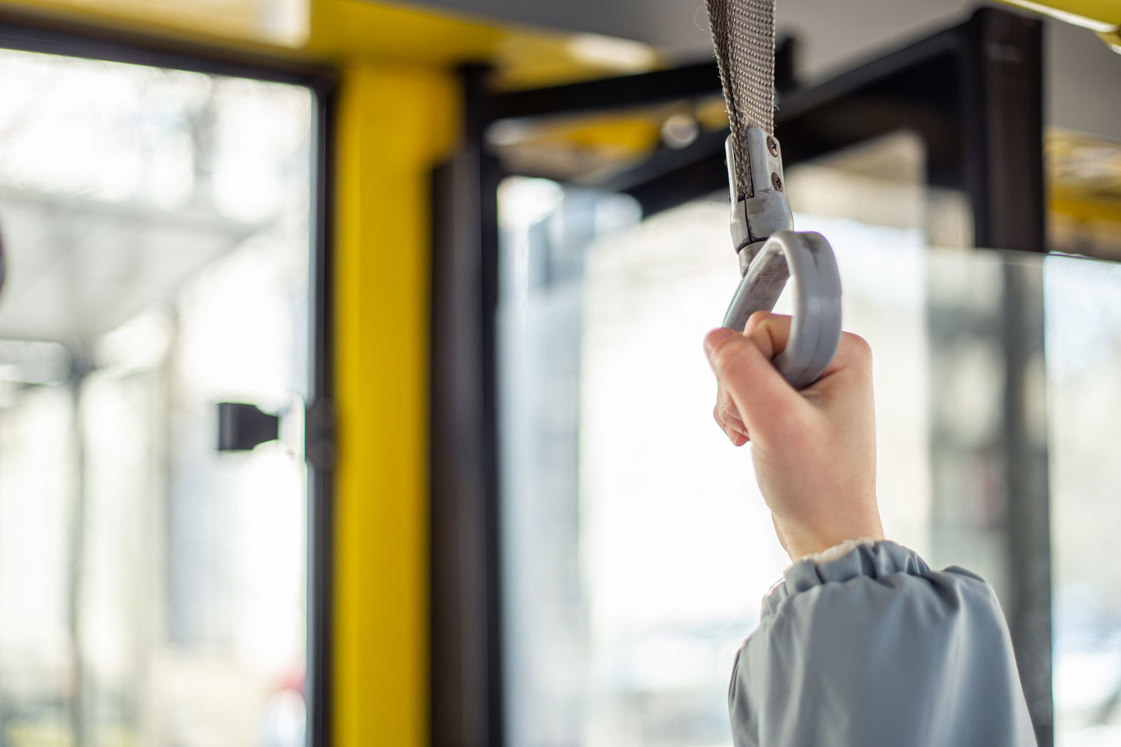 Eine Person hält sich am Griff in einem Bus