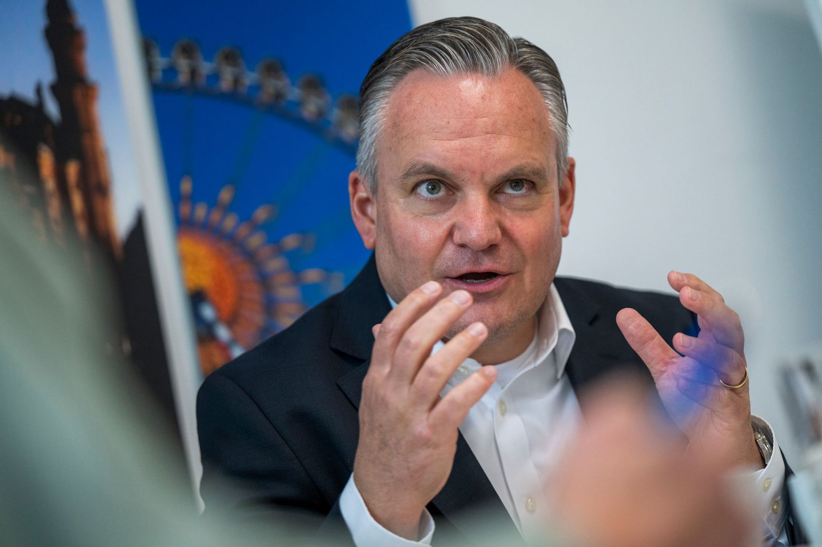 Münches neuer Wiesnchef Scharpf vor einem Foto des Riesenrades. 