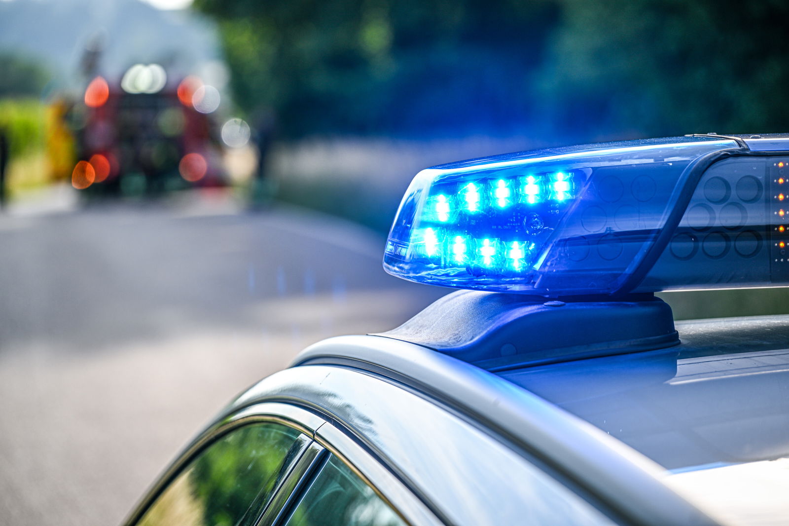 Eine Unfallstelle mit einem Polizeiwagen mit Blaulicht im Vordergrund