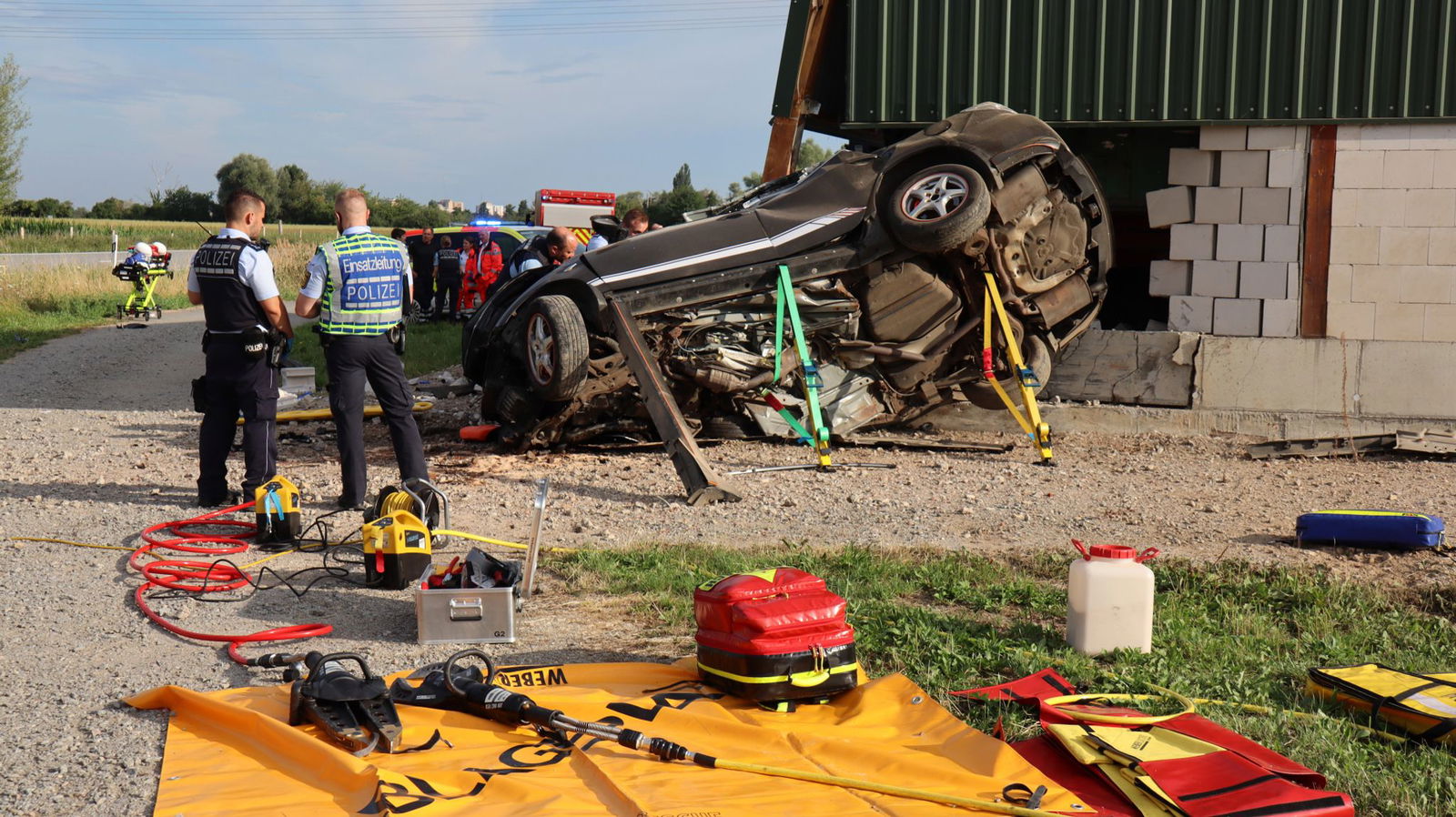 Polizei und Rettungsdienste stehen an dem Fahrzeugwrack.