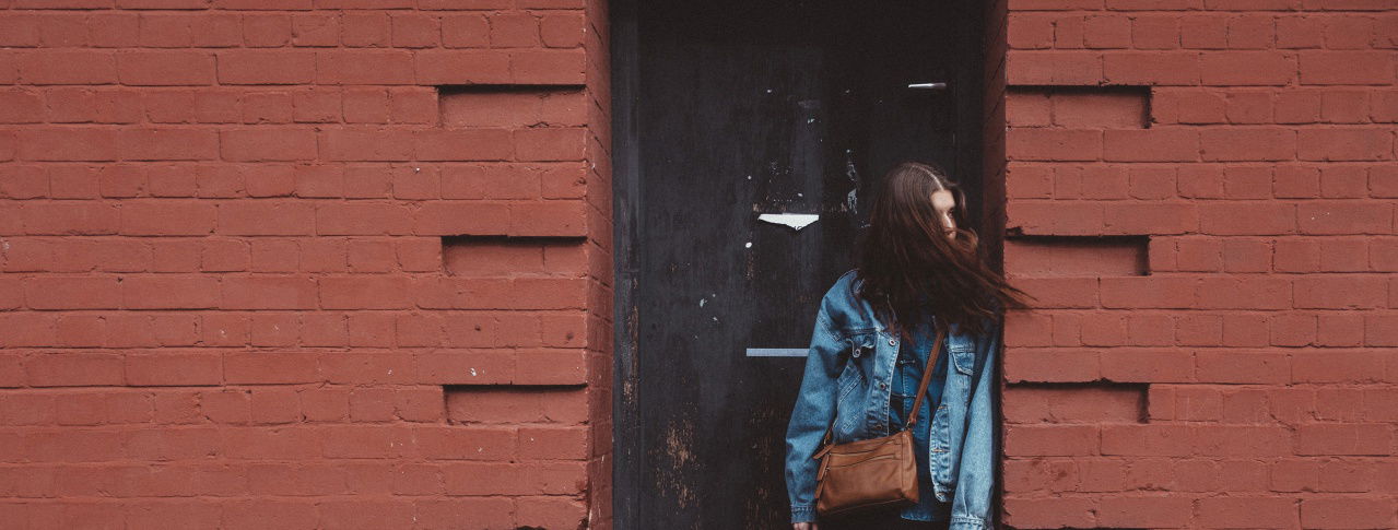 Mädchen schaut nach rechts vor Backsteinhaus