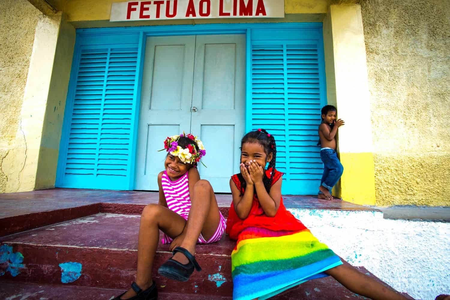 Zwei Mädchen aus Tuvalu sitzen lachend auf den Stufen der Fētu'ao Lima Church, der staatlichen Kirche auf dem Funafuti-Atoll. 