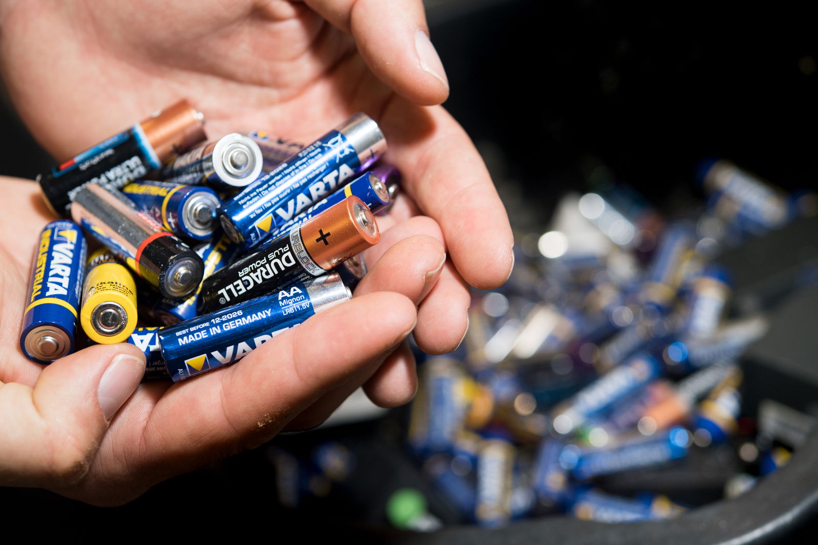 Ein Mann hält zahlreiche Batterien in der Hand