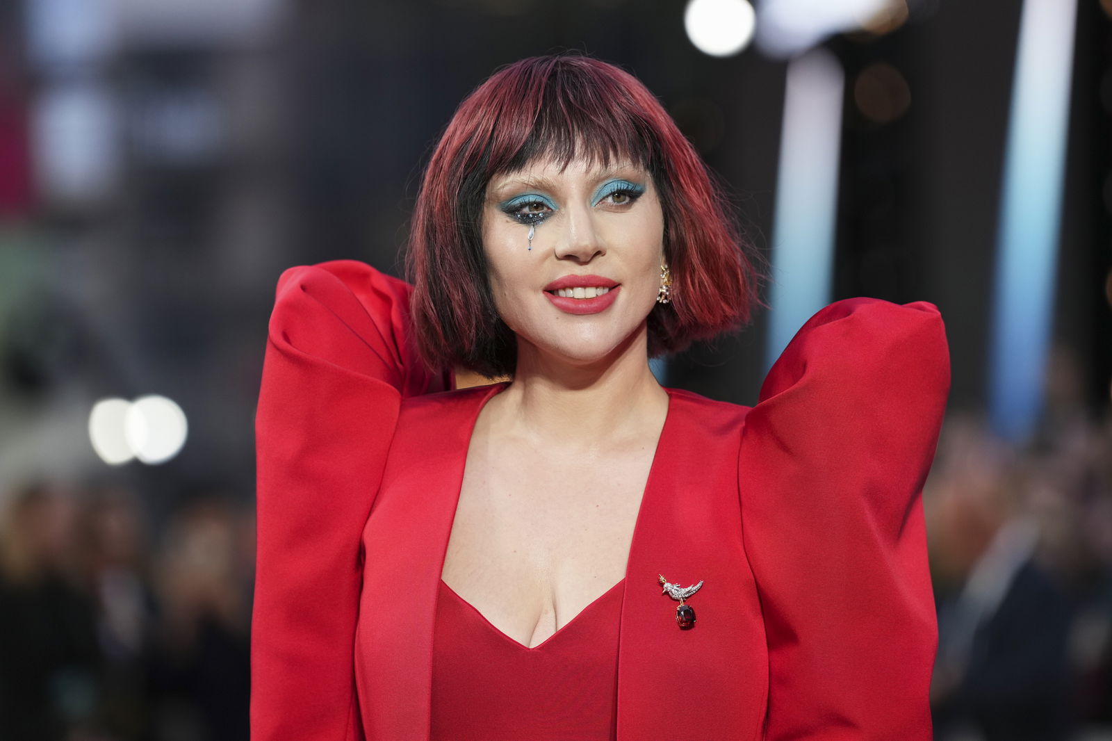 Lady Gaga lächelt in die Kamera. Sie trägt ein rotes Kleid.