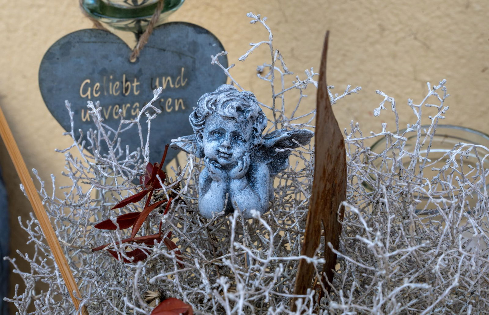 Eine Engelsfigur und ein Herz mit einem Gedenkspruch sind vor dem Hotel aufgestellt, das vor einem Jahr in Kröv an der Mosel eingestürzt war.