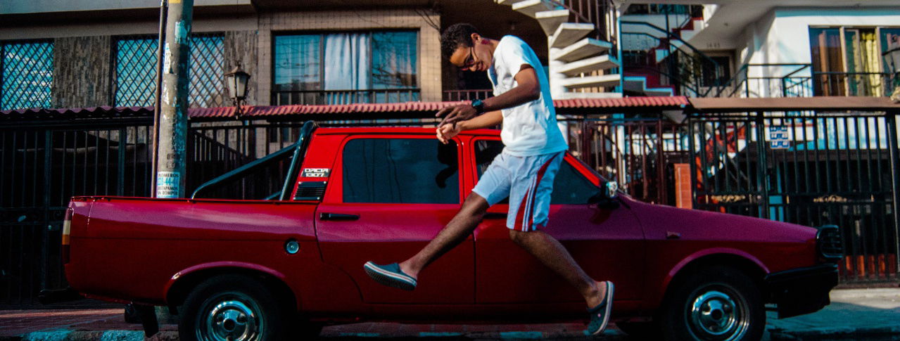 mann springt vor rotem auto