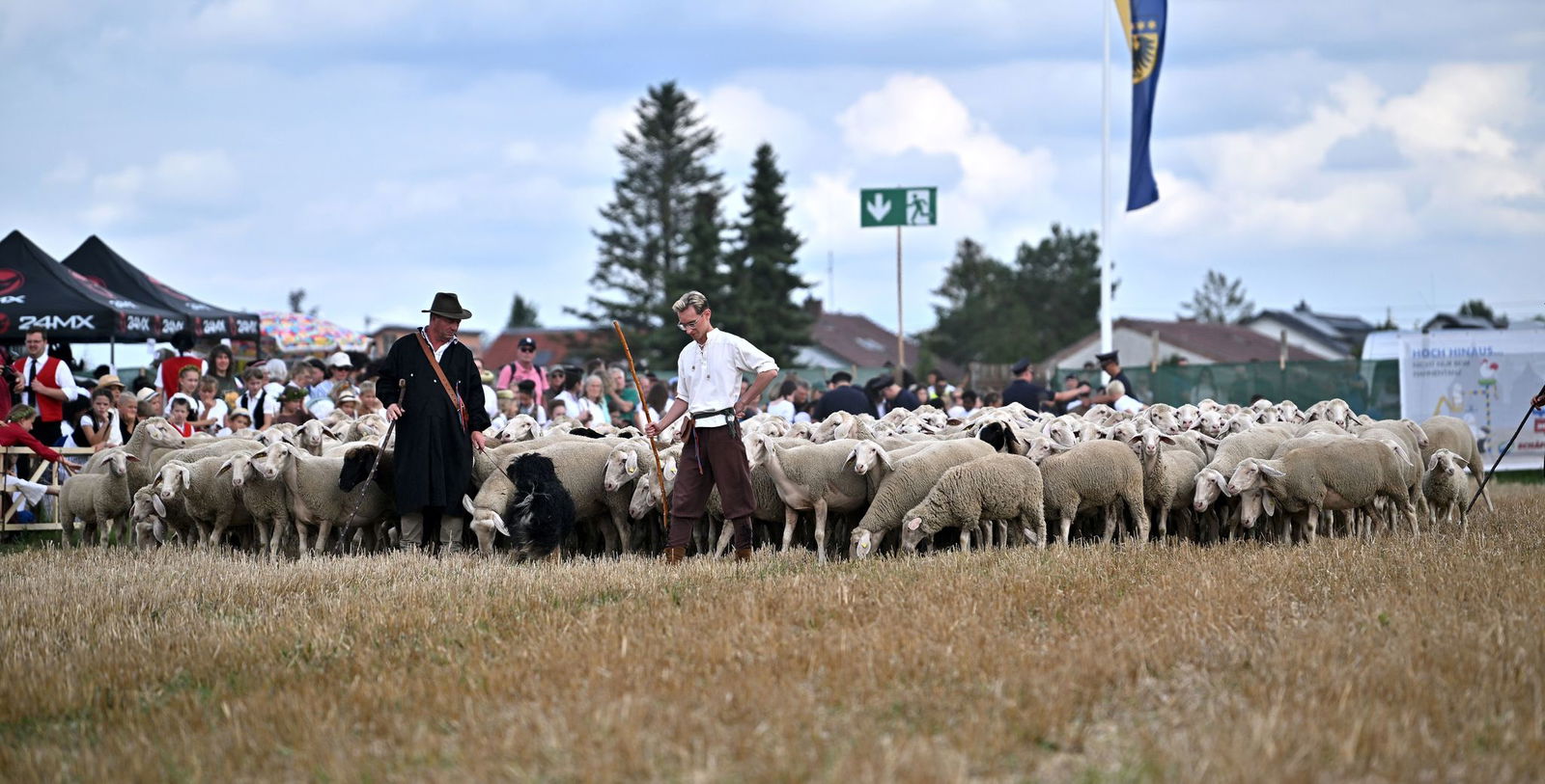 Schäferinnen und Schäfer laufen barfuß über ein Stoppelfeld.
