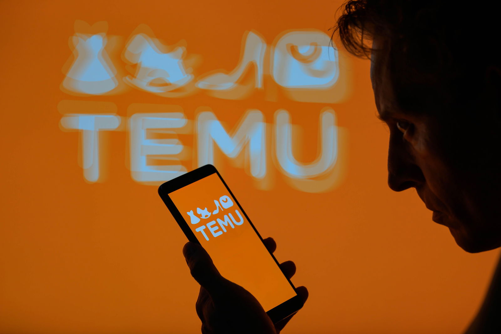  Mann blickt auf sein Smartphone mit geöffneter Temu-App - im Hintergrund das leuchtende Temu-Logo.
