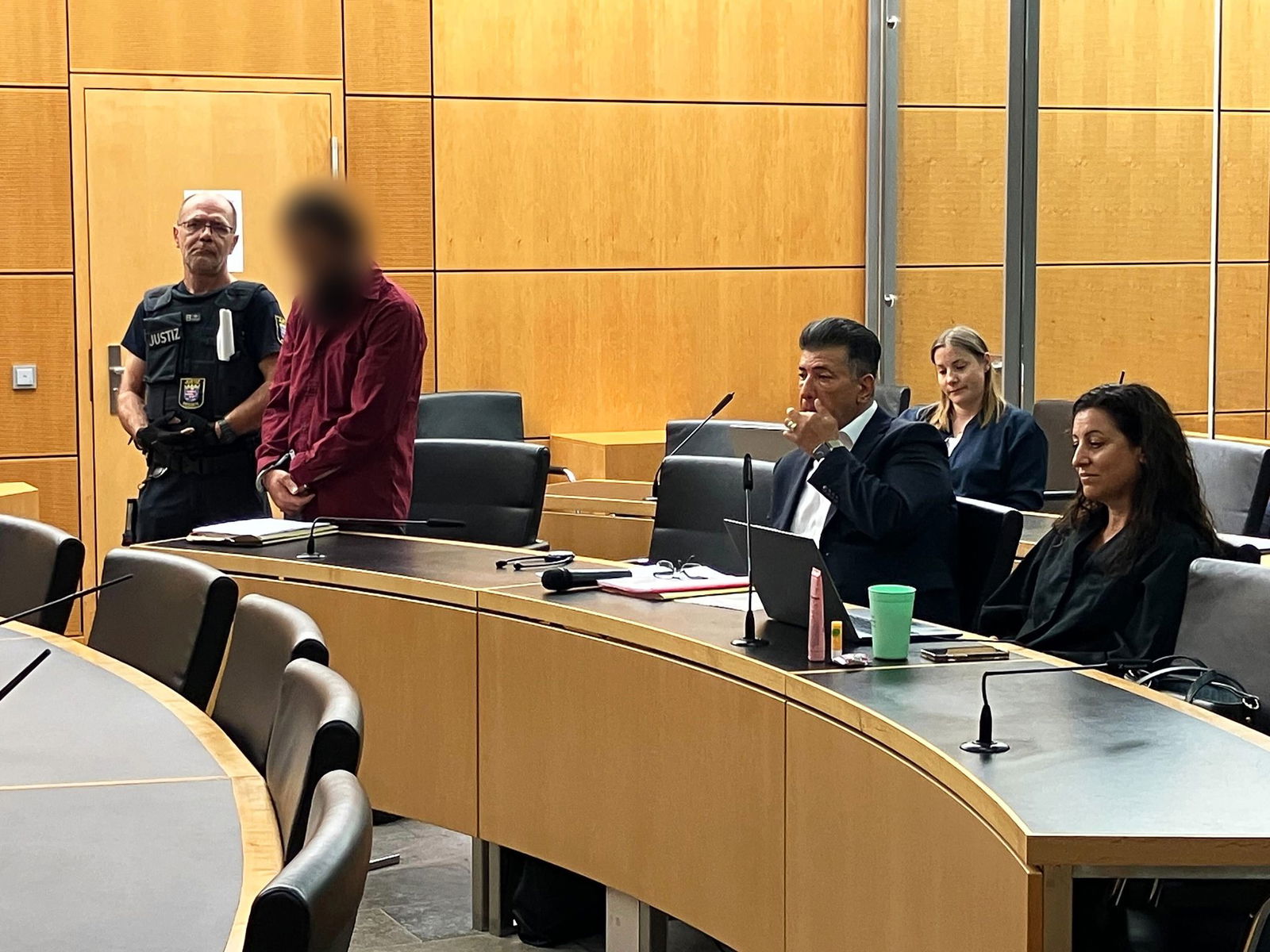 Der Angeklagte will sich nicht setzen: Er lehnt die Pflichtverteidigerin ab.