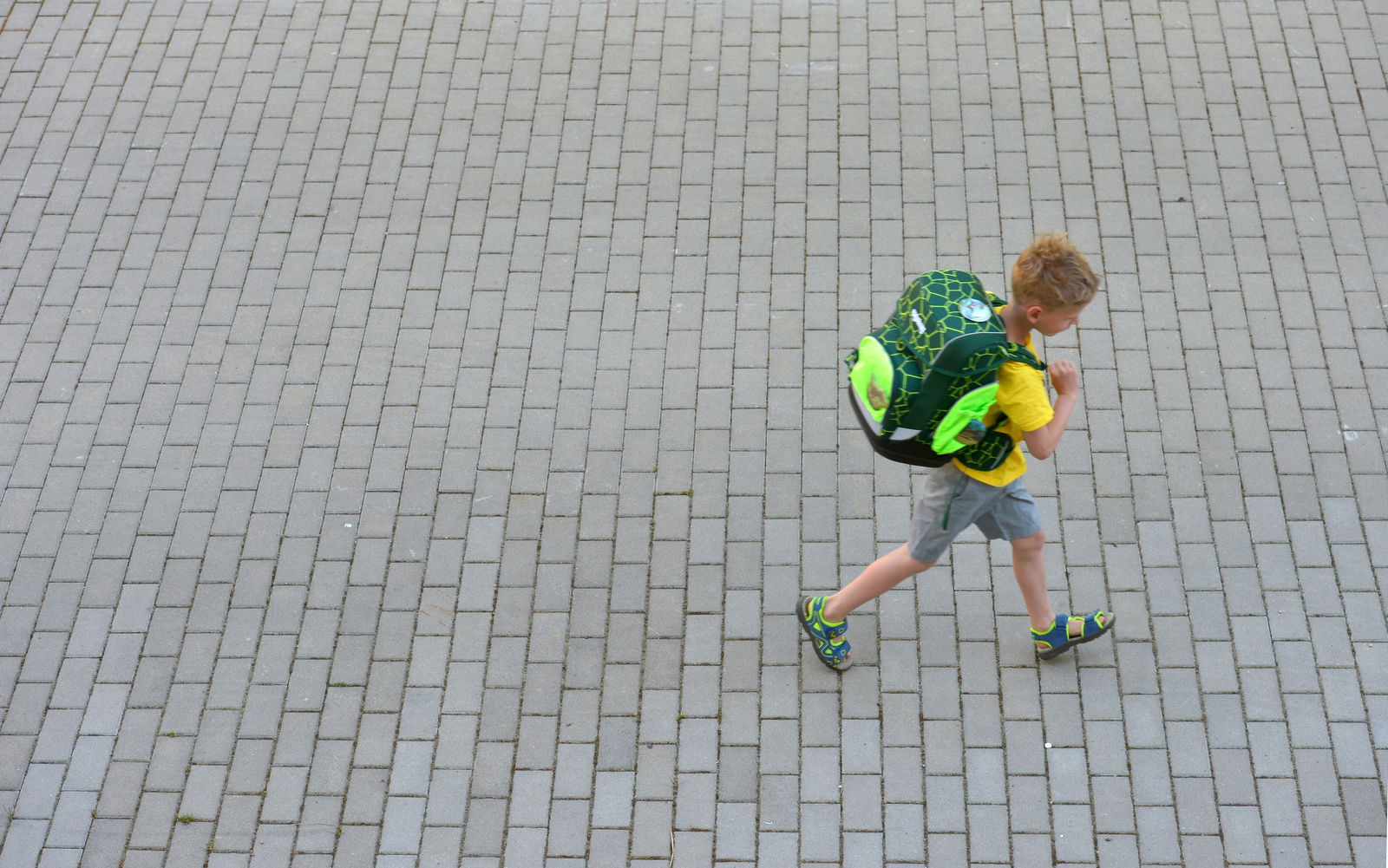 Junge mit Ranzen auf dem Rücken auf dem Schulweg