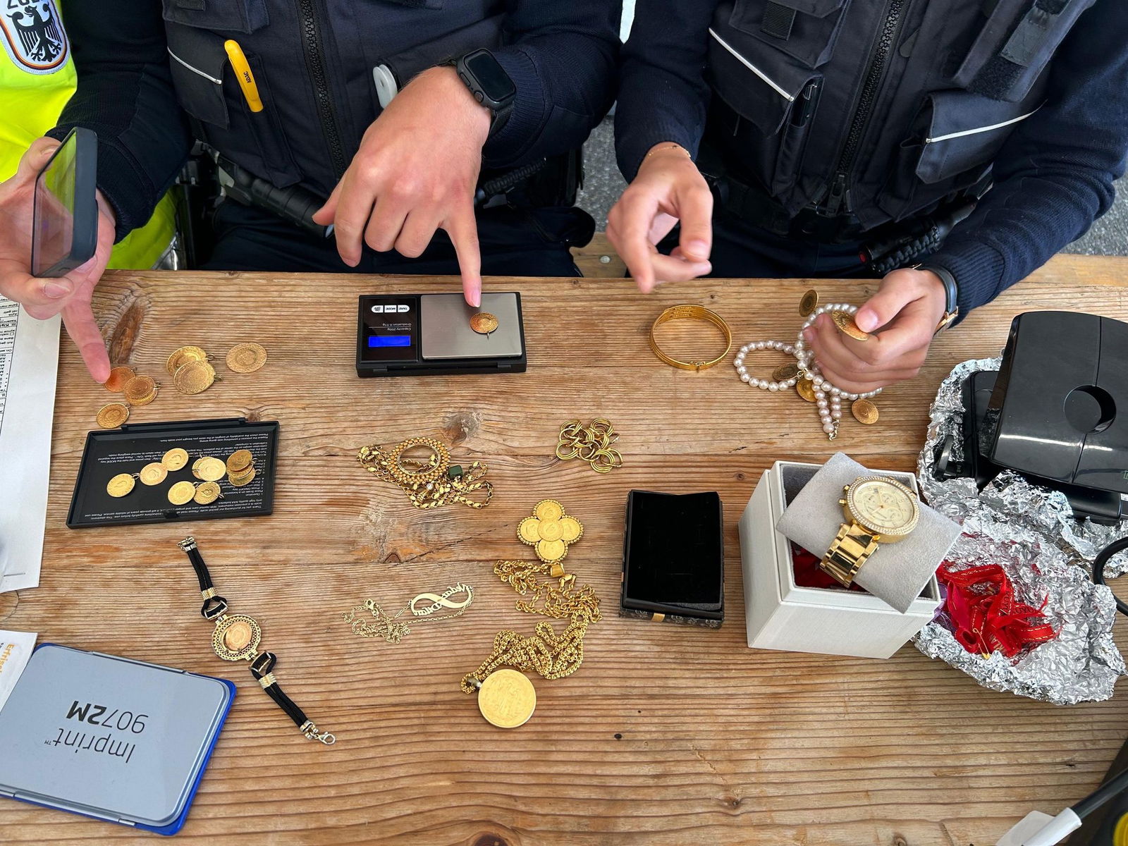 Die Zollbeamten wiegen den sichergestellten Goldschmuck.