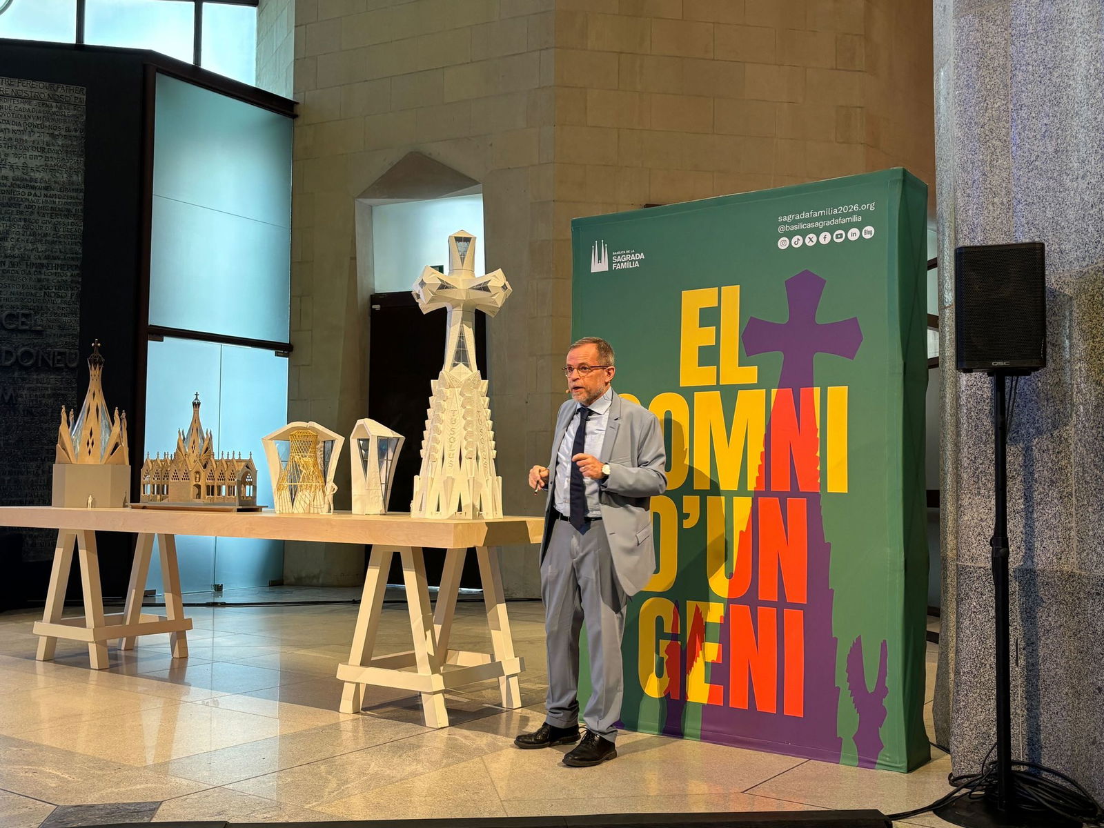 Der leitende Architekt der Sagrada Familia, Jordi Faulí, erklärt vor einem großen Poster den Aufbau des großen Kreuzes aus Deutschland für den Hauptturm der Basilika.