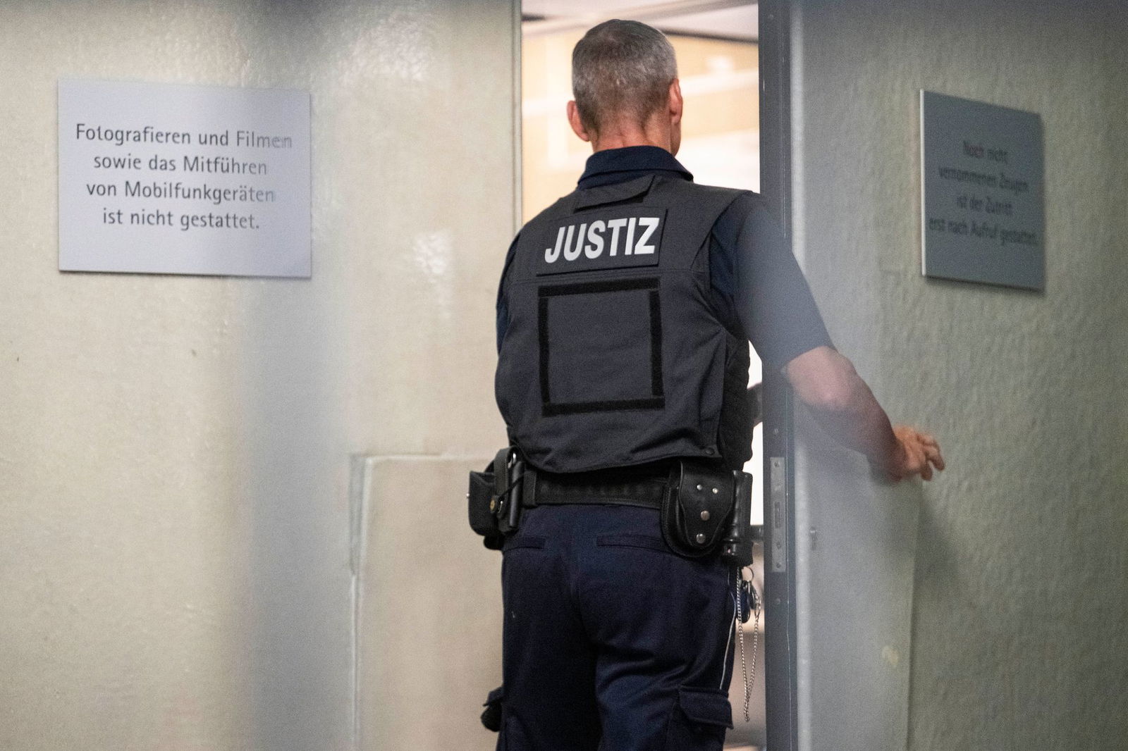 Ein Justizbeamter schließt beim Auftakt im Prozess gegen drei mutmaßliche IS-Sympathisanten die Tür zu einem Saal des Landgerichts Mannheim.