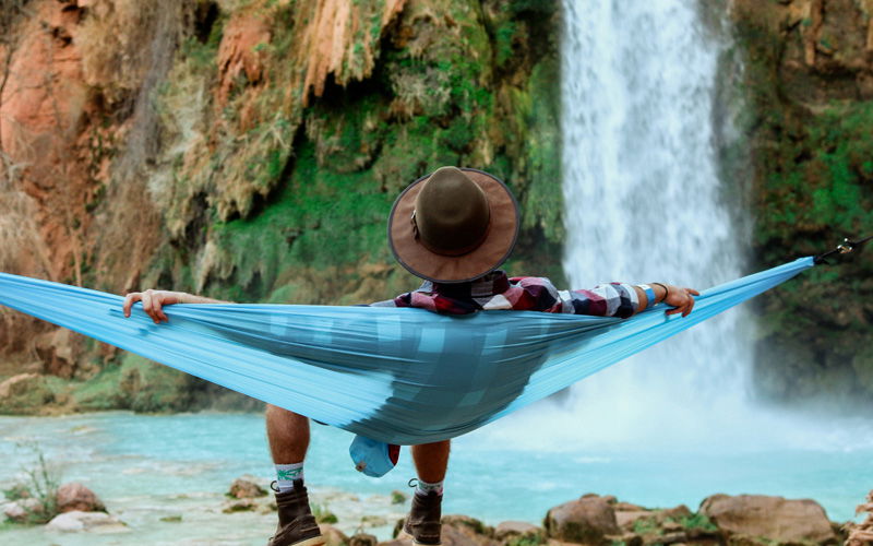 Mann in einer Hängematte an einem Wasserfall