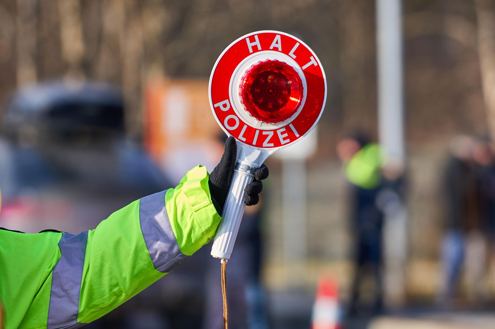 Polizist hält Polizeikelle hoch