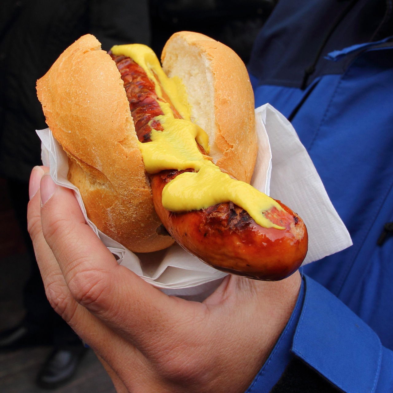 Person hält Bratwurstbrötchen in der Hand