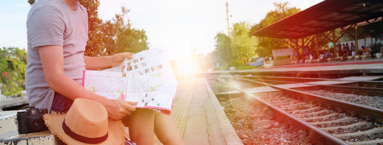 Mann sitzt mit Karte am Bahnsteig
