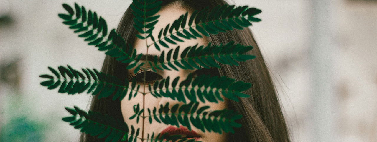 Frau hebt ein Blatt vor ihr Gesicht 