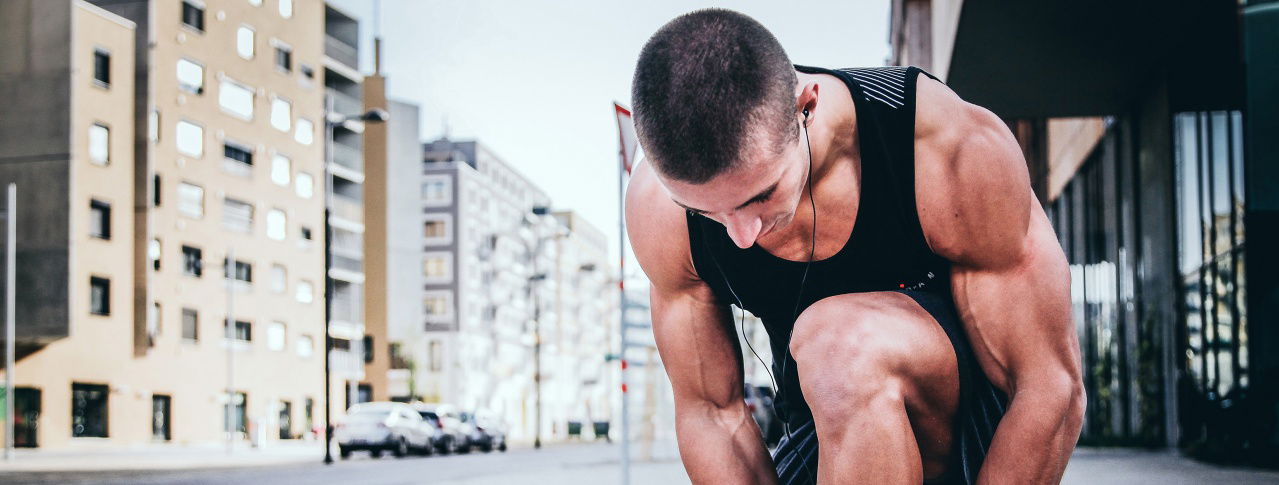 Mann mit stark zusehenden Muskeln bindet sich die Schuhe