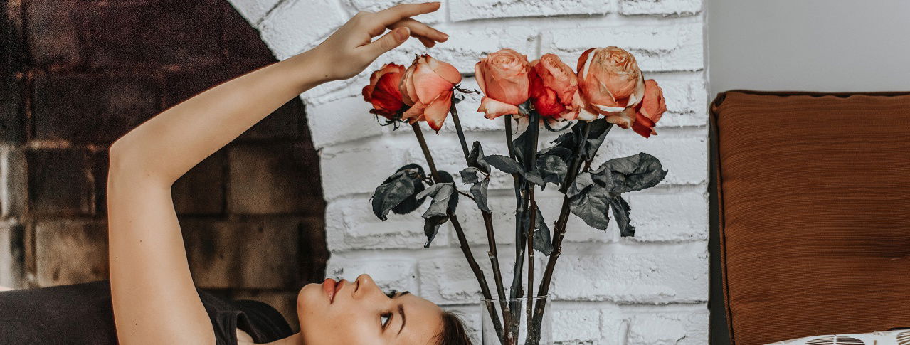 Mädchen liegt auf dem Boden, schaut Rosen an und berührt sie 