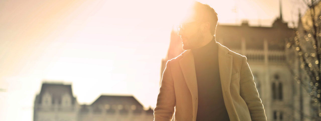 Mann steht vor untergehender Sonne und schaut zur Seite