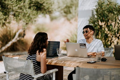man und frau sitzen mit laptops in gartenlounge