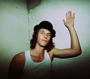 mann mit hut vor betonwand