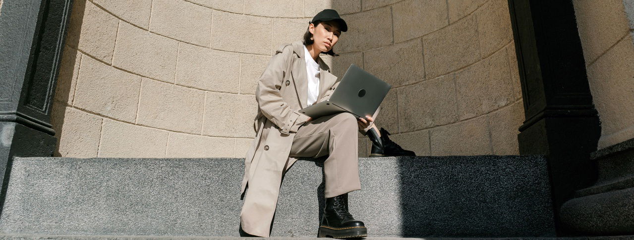 Frau mit Laptop sitzt und schaut in die Kamera