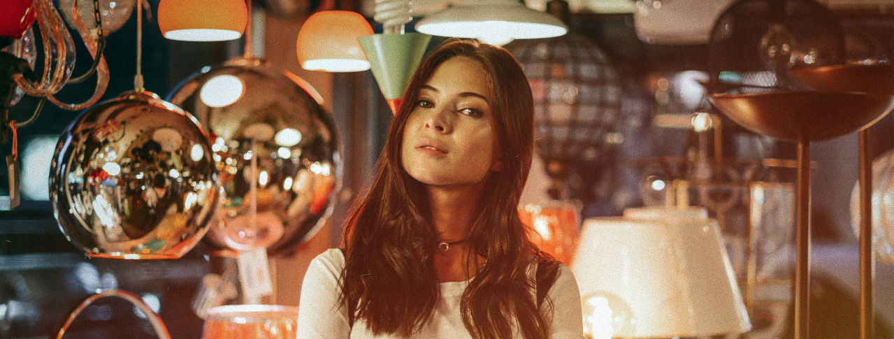 Frau schaut in die Kamera in einem Raum voller Lampen