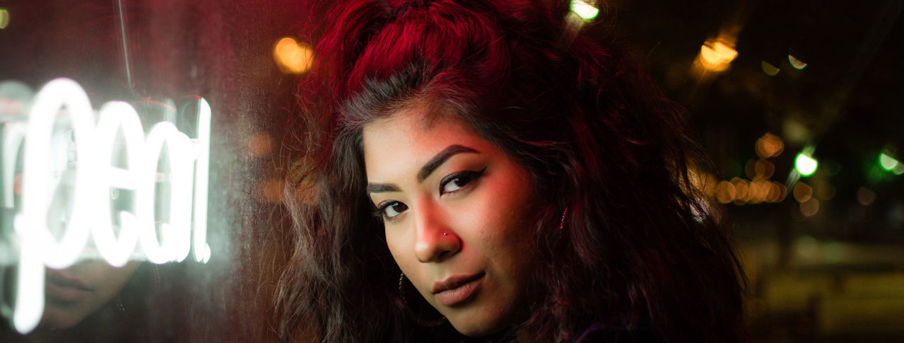 Frau vor Lichtschrift schaut verschmitzt in die Kamera